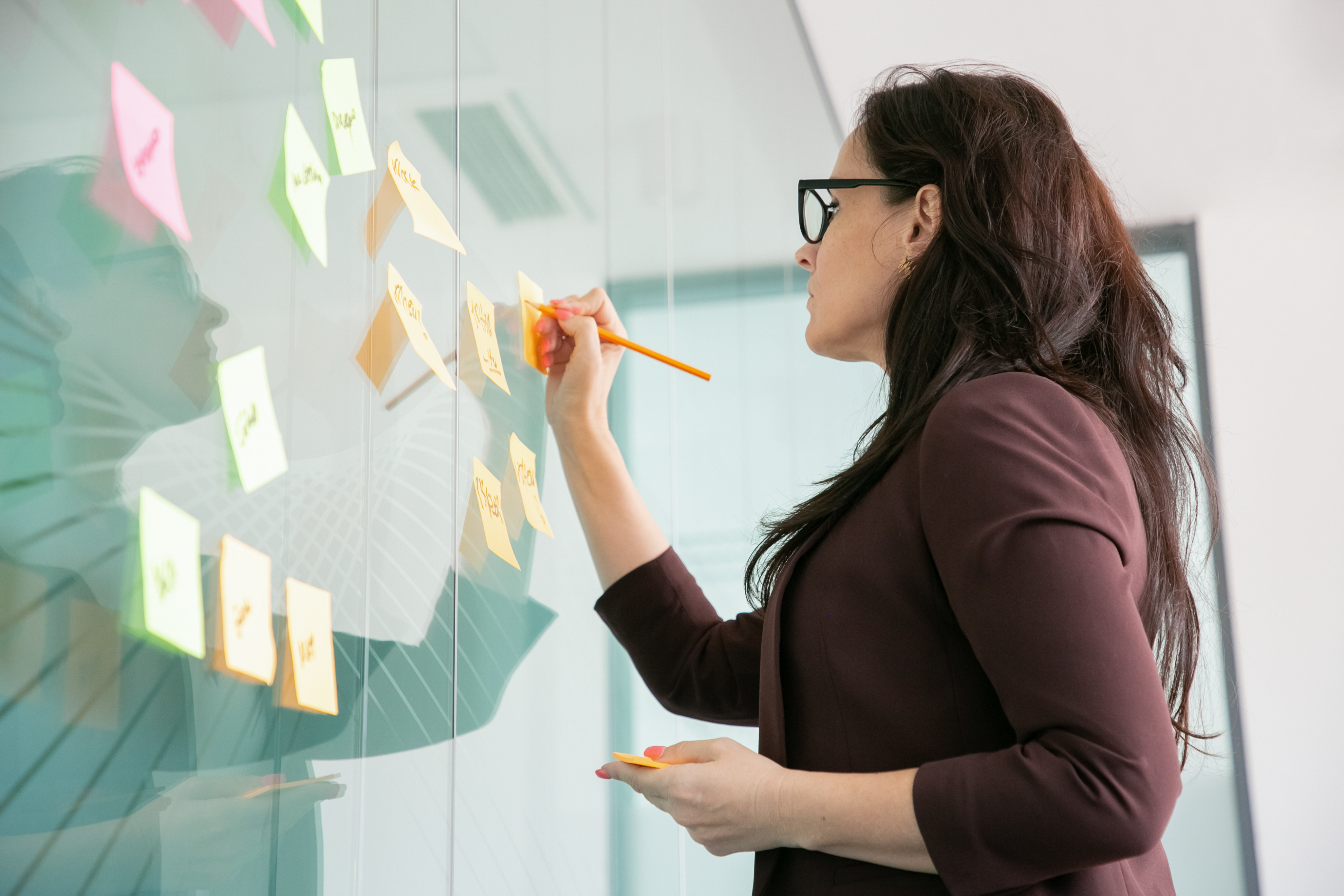 confident-middle-aged-businesswoman-writing-sticker-with-pencil-brainstorming
